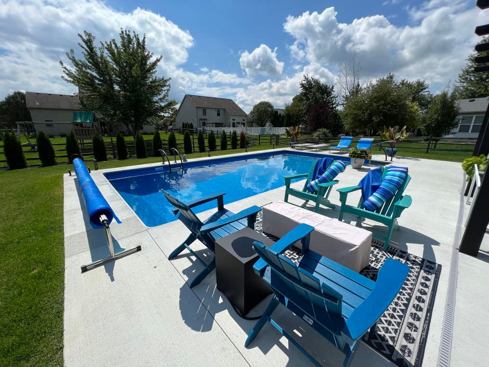 Beautiful backyard pool with blue loungers, sunny skies, and lush greenery. Perfect for summer relaxation.